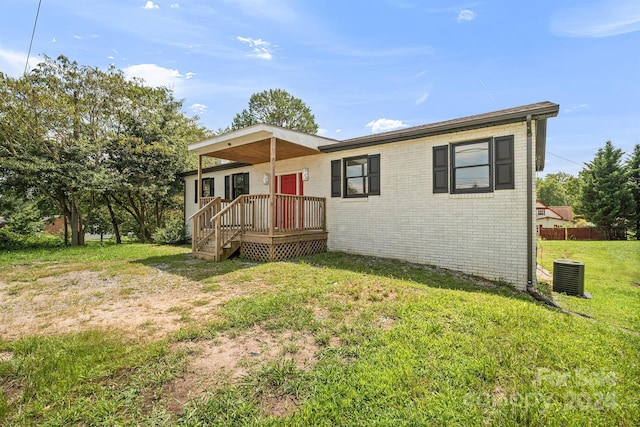 view of front of property with brick siding, a front yard, and cooling unit