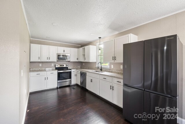 kitchen featuring appliances with stainless steel finishes, sink, crown molding, white cabinets, and dark wood-type flooring