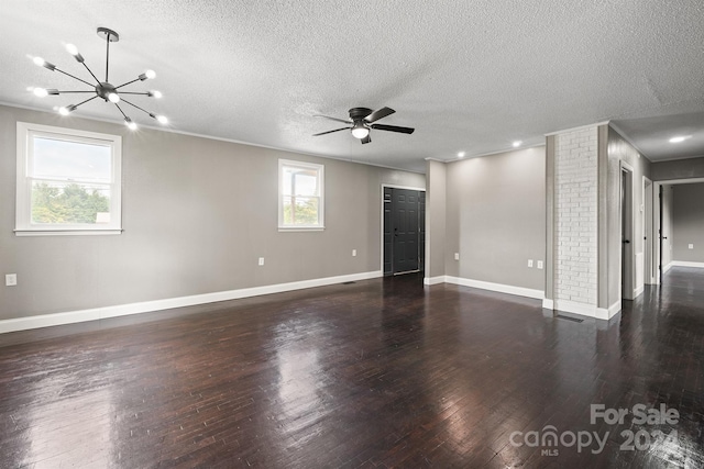 empty room with wood-type flooring, ceiling fan with notable chandelier, a textured ceiling, crown molding, and brick wall