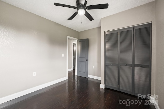 unfurnished bedroom featuring a closet, ceiling fan, a textured ceiling, wood finished floors, and baseboards