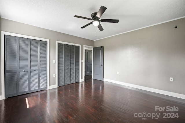 unfurnished bedroom featuring ceiling fan, hardwood / wood-style floors, ornamental molding, two closets, and a textured ceiling