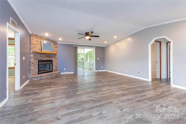 unfurnished living room featuring ceiling fan, crown molding, wood-type flooring, and a stone fireplace