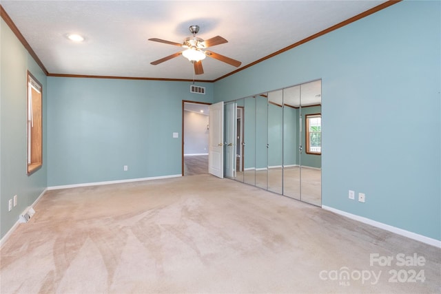 unfurnished bedroom featuring ornamental molding, a closet, ceiling fan, and carpet flooring