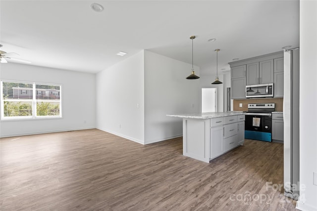 kitchen featuring wood-type flooring, a kitchen island, stainless steel appliances, pendant lighting, and gray cabinets