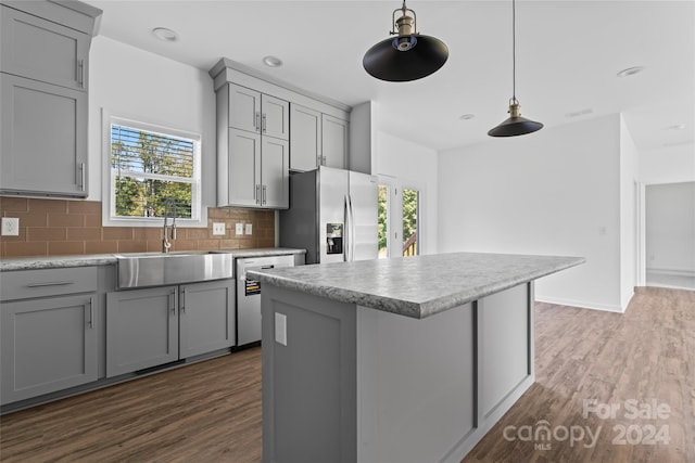 kitchen with dark wood-type flooring, gray cabinetry, stainless steel appliances, and a healthy amount of sunlight