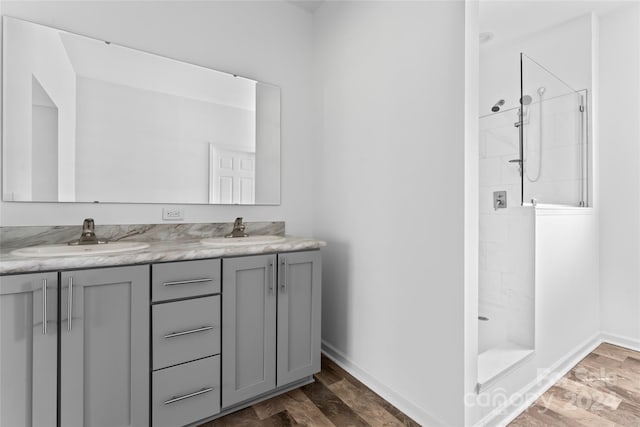 bathroom with vanity, hardwood / wood-style flooring, and tiled shower