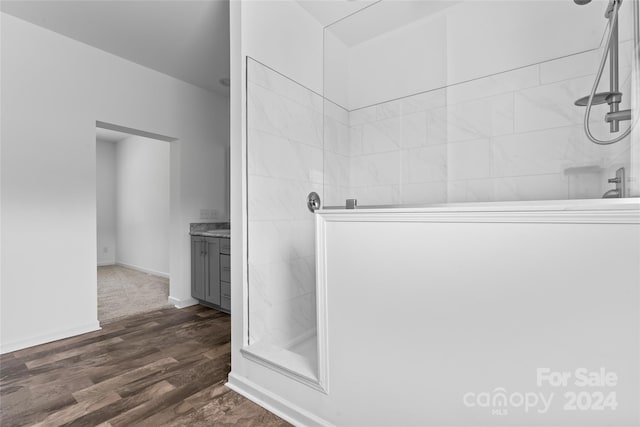 bathroom with vanity, tiled shower, and wood-type flooring