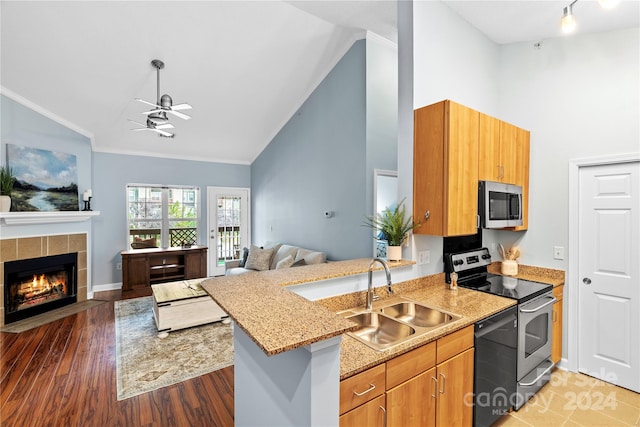 kitchen with a tile fireplace, stainless steel appliances, sink, kitchen peninsula, and ceiling fan