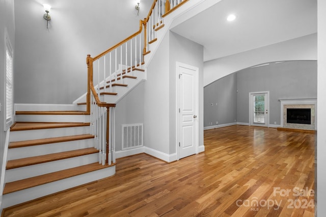 staircase with wood-type flooring and a towering ceiling