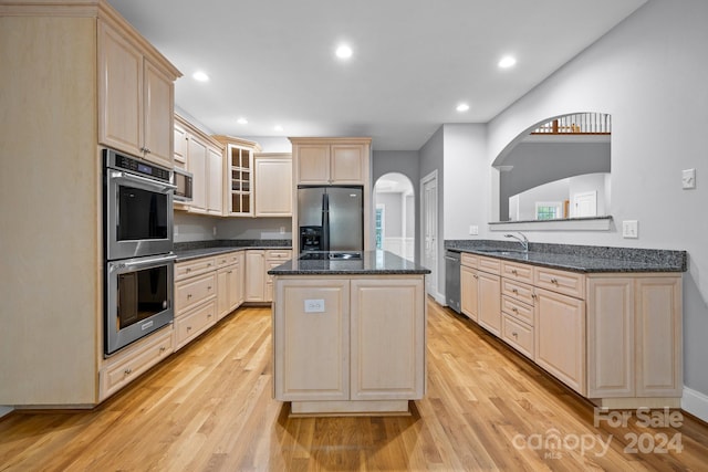 kitchen with dark stone counters, sink, stainless steel appliances, and light wood-type flooring