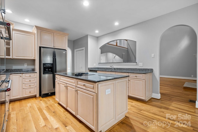 kitchen with a center island, dark stone counters, sink, appliances with stainless steel finishes, and light hardwood / wood-style floors