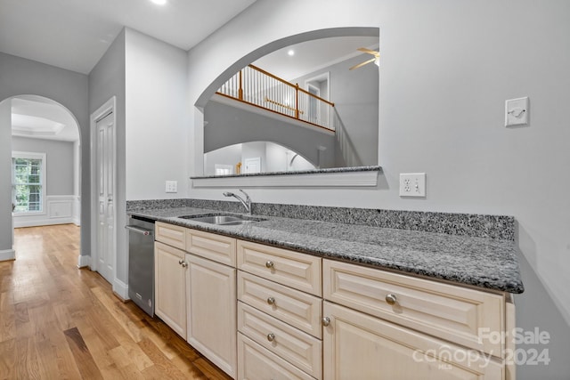 kitchen featuring light wood-type flooring, ceiling fan, dark stone counters, and sink