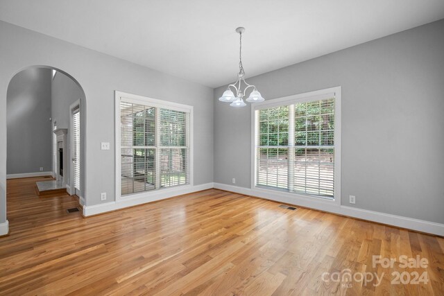 unfurnished dining area featuring hardwood / wood-style floors and an inviting chandelier