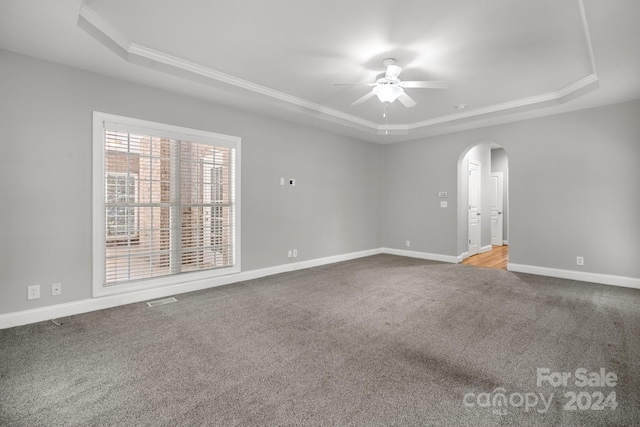 unfurnished room featuring a tray ceiling, ceiling fan, crown molding, and carpet floors