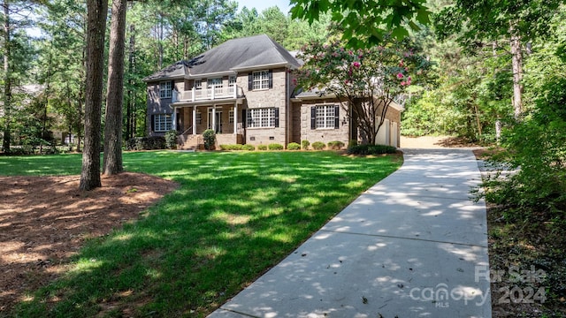 colonial inspired home with a front yard, a balcony, and a garage