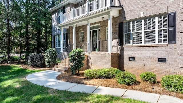 view of exterior entry featuring a balcony and covered porch