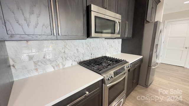 kitchen featuring light wood-type flooring, crown molding, stainless steel appliances, decorative backsplash, and dark brown cabinetry