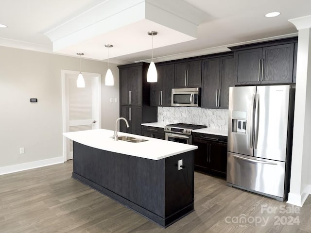 kitchen with backsplash, light wood-type flooring, appliances with stainless steel finishes, sink, and an island with sink