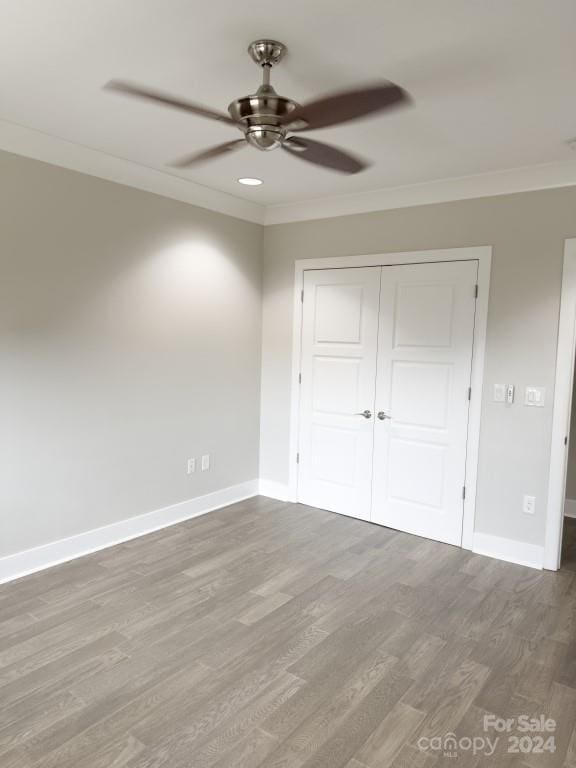 unfurnished bedroom with crown molding, ceiling fan, a closet, and wood-type flooring