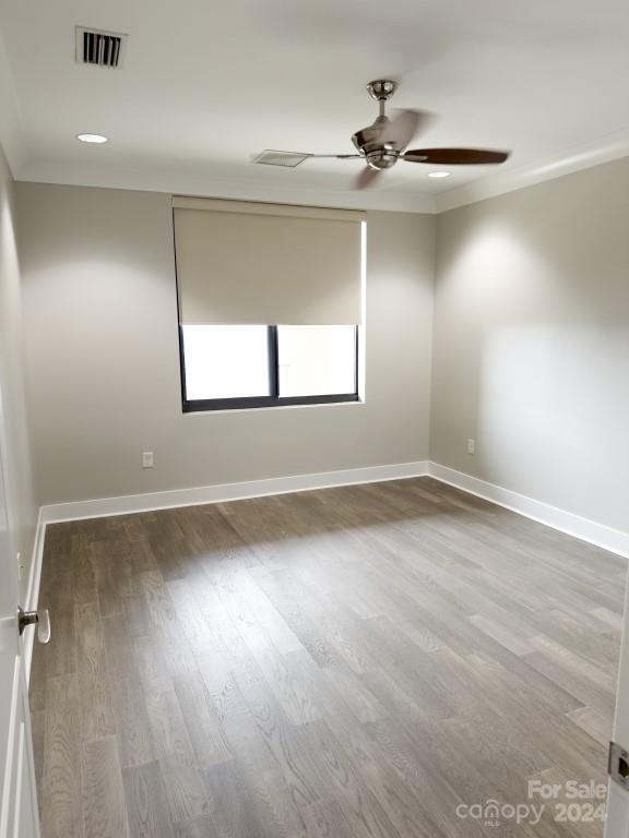 empty room with crown molding, hardwood / wood-style floors, and ceiling fan