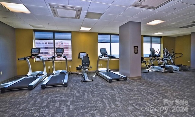 exercise room with dark carpet and a drop ceiling