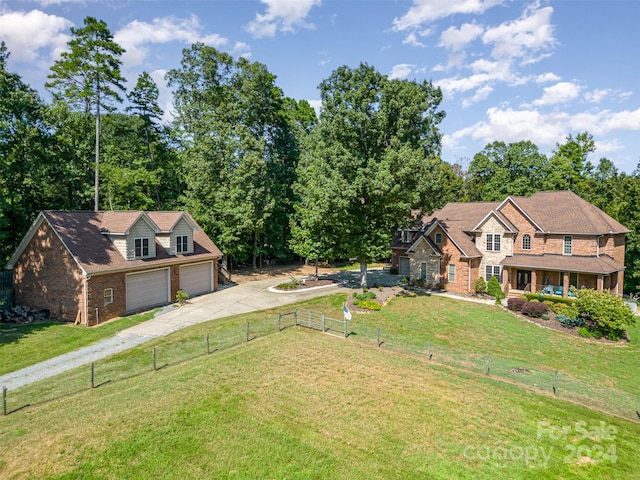 traditional home featuring a garage, brick siding, fence, driveway, and a front lawn