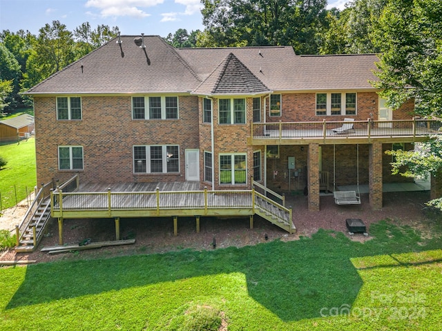 rear view of property with a deck, brick siding, a shingled roof, a yard, and stairway