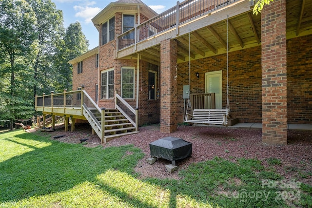 back of property featuring brick siding, a yard, stairway, and a wooden deck