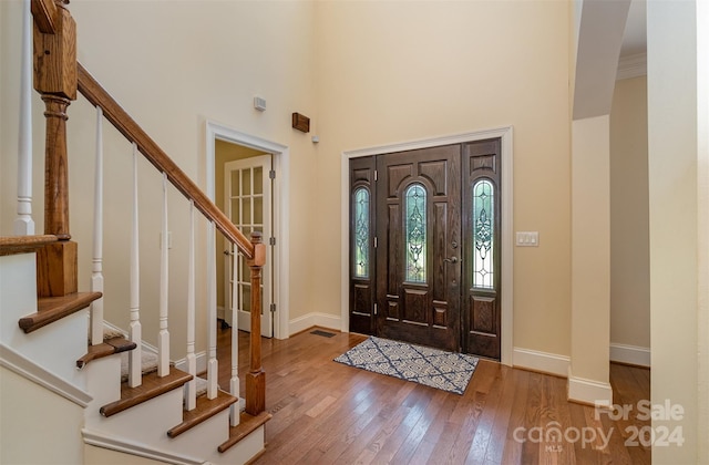 entryway with a high ceiling, baseboards, stairway, and hardwood / wood-style floors