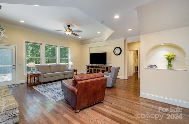 living room featuring ceiling fan, a tray ceiling, hardwood / wood-style floors, and ornamental molding