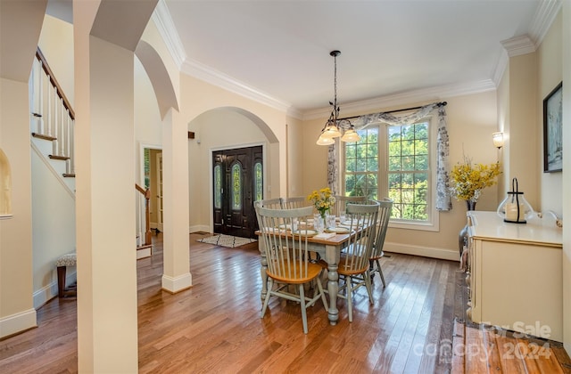 dining room with ornamental molding, stairway, light wood-style flooring, and baseboards