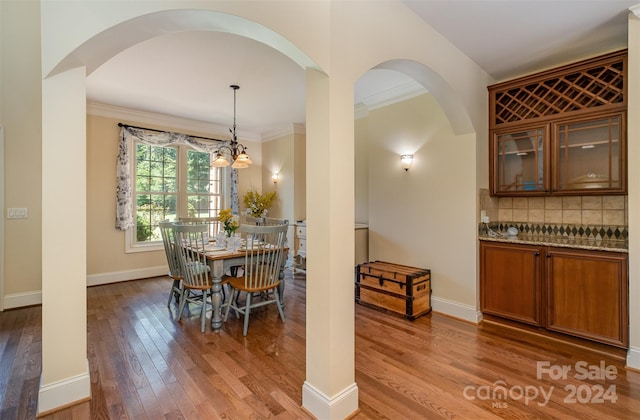 dining room with hardwood / wood-style floors, an inviting chandelier, and ornamental molding