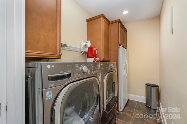 laundry room with cabinets, dark tile patterned floors, and washer and clothes dryer