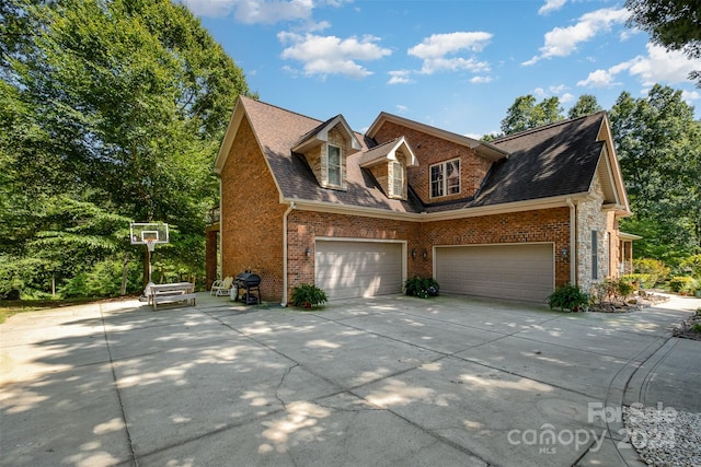 view of property exterior with brick siding, driveway, and roof with shingles