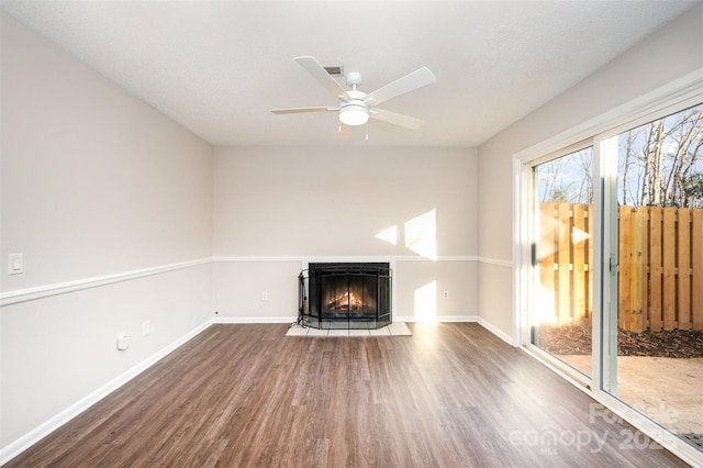 unfurnished living room featuring dark wood-type flooring, ceiling fan, and a multi sided fireplace