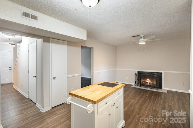 kitchen with dark wood-type flooring, ceiling fan, white cabinetry, butcher block counters, and a textured ceiling