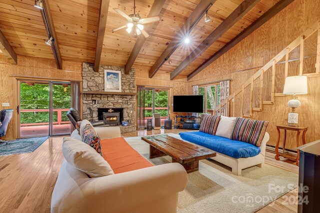 living room with a fireplace, wooden walls, vaulted ceiling with beams, wooden ceiling, and hardwood / wood-style flooring