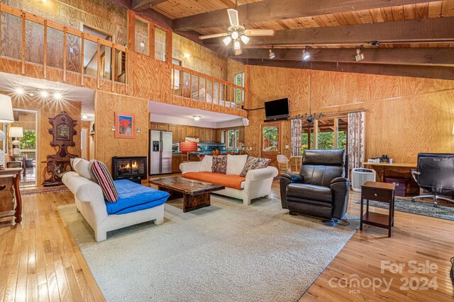 living room with light wood-type flooring, high vaulted ceiling, wooden walls, and wooden ceiling