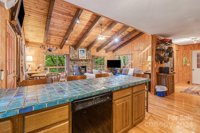 kitchen featuring tile countertops, dishwasher, wooden walls, and vaulted ceiling with beams