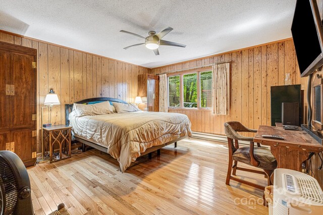 bedroom with wood walls, ceiling fan, and light hardwood / wood-style floors