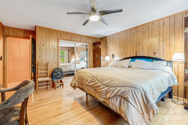 bedroom featuring light hardwood / wood-style flooring, ceiling fan, and wooden walls