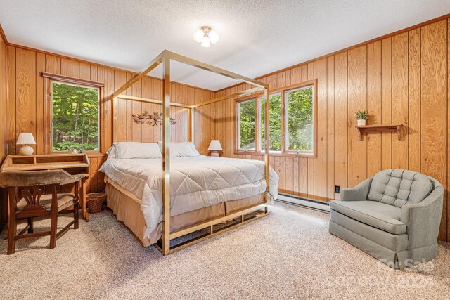 carpeted bedroom featuring multiple windows, baseboard heating, and wooden walls