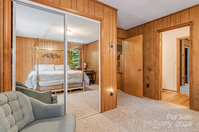 carpeted bedroom featuring wood walls and a textured ceiling