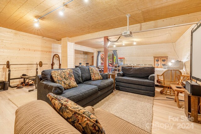 living room featuring wood walls, light wood-type flooring, decorative columns, and track lighting