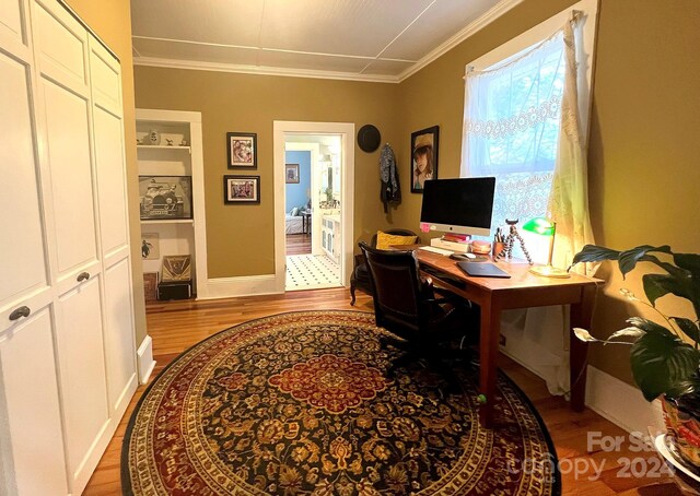 office area featuring crown molding, light hardwood / wood-style flooring, and built in shelves