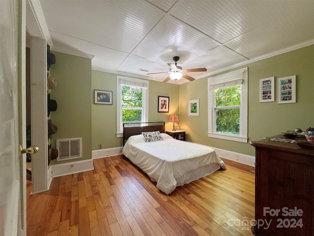 bedroom featuring multiple windows, ceiling fan, light hardwood / wood-style floors, and ornamental molding