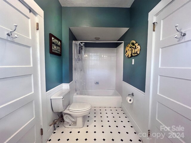 bathroom featuring tile patterned flooring, toilet, shower / tub combo with curtain, and a textured ceiling