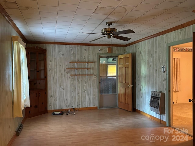 spare room featuring wooden walls, ceiling fan, heating unit, and wood-type flooring