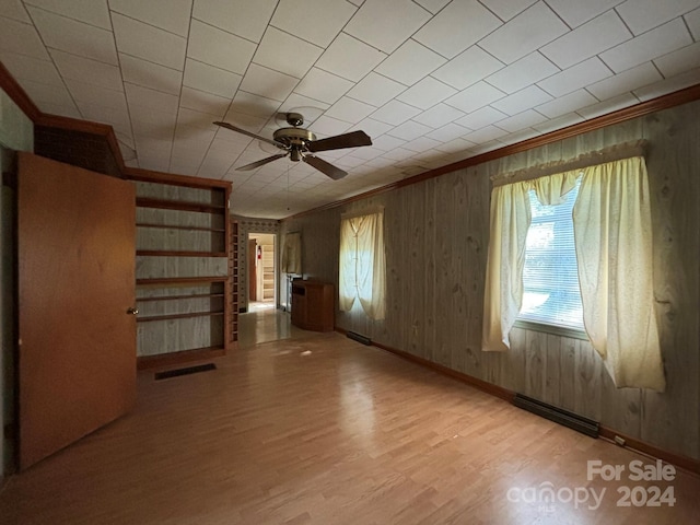 spare room with ceiling fan, light wood-type flooring, and wood walls