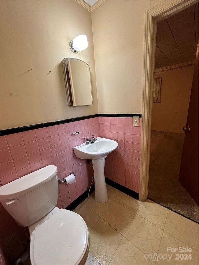 bathroom with crown molding, toilet, tile patterned floors, and tile walls